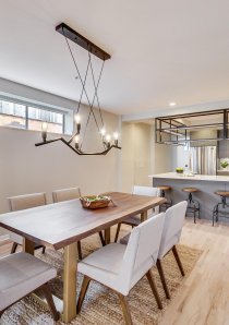 dining room with wooden dining table and grey chairs underneath contemporary chandelier light in Chicago apartment for rent