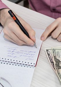 a landlord using a notepad to calculate how much rent to charge for an apartment listing