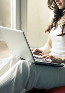 woman in grey tanktop using a silver laptop computer 
