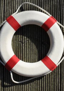 red and white lifesaver ring hanging on metal wall