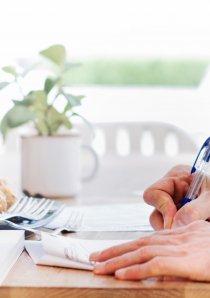 person signing an apartment lease form on a wooden desk