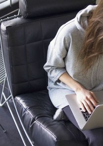 apartment renter using a laptop computer while seated on a black leather lounge chair