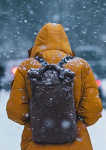 a person wearing a yellow snow parka and backpack during snowy weather