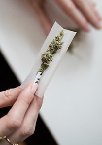 woman rolling cannabis into cigarette paper