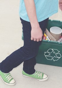 a person dropping a plastic bottle into a green recycling bin