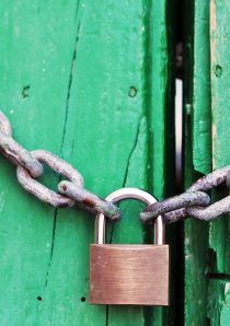 a padlock and steel chain on a green wooden door
