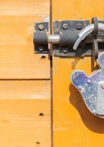 a steel padlock hanging on a yellow wooden door