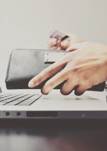 renter taking credit card out of wallet to pay online utility bills with their laptop