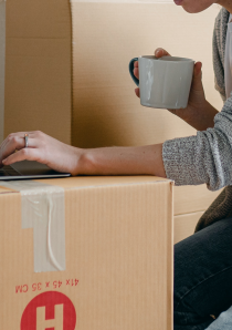 apartment renter using laptop computer balanced on top of moving boxes