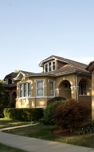 two story brick house with shrubs in front and green grass yard in front in Montclare Chicago